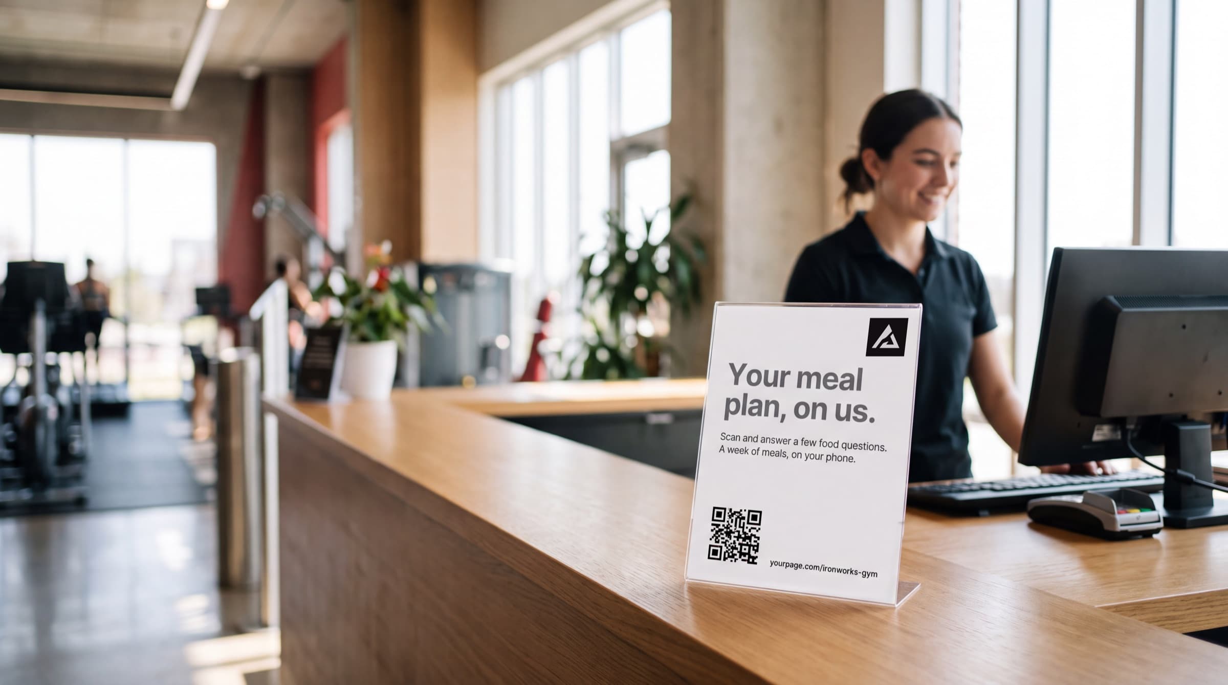 A gym reception desk with a branded meal plan card standing on the counter
